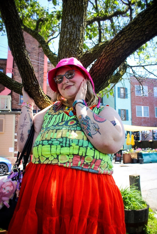 Colorful street-style outfit featuring green graphic top, red skirt and pink bucket hat