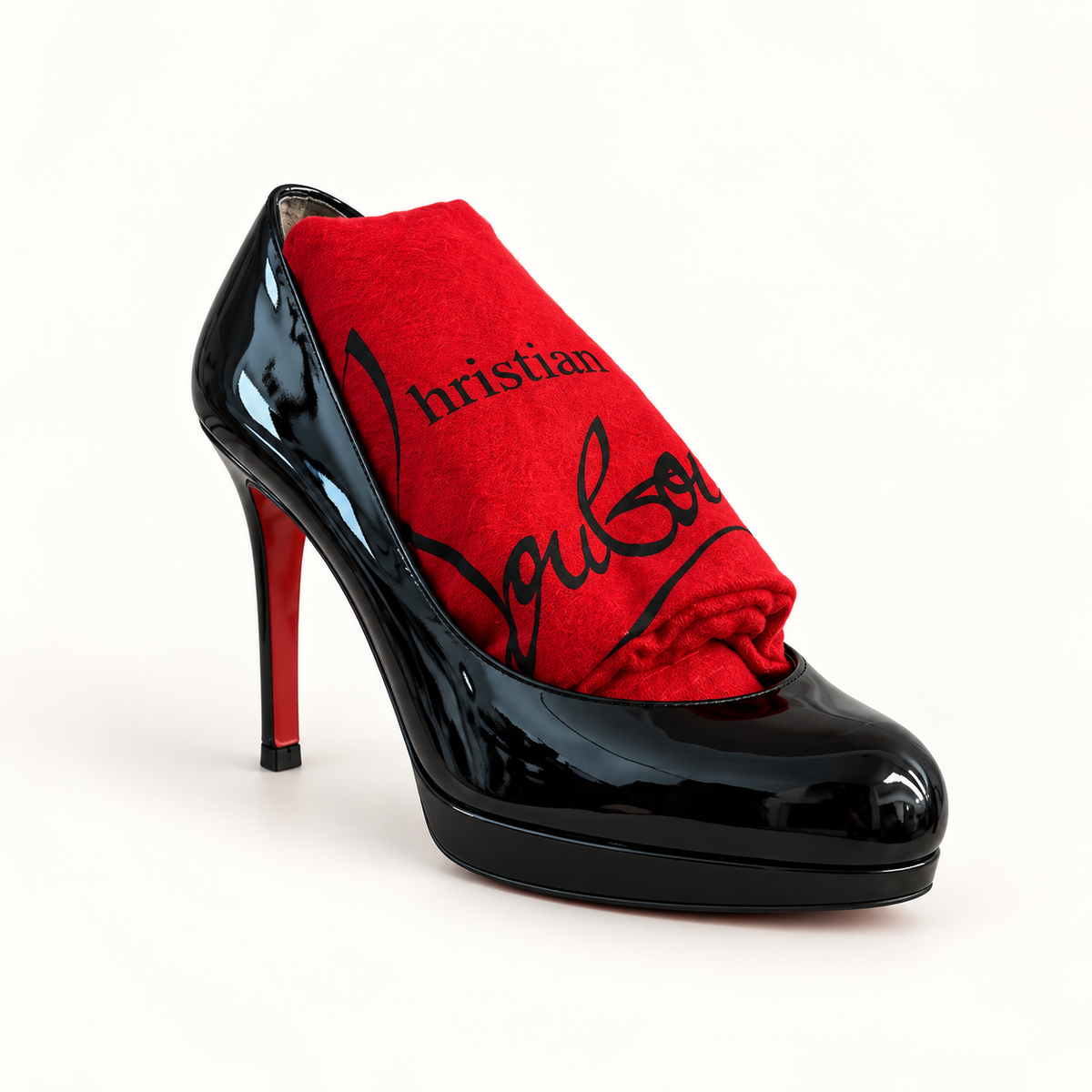 Christian Louboutin black patent pump with red dust bag on off white background