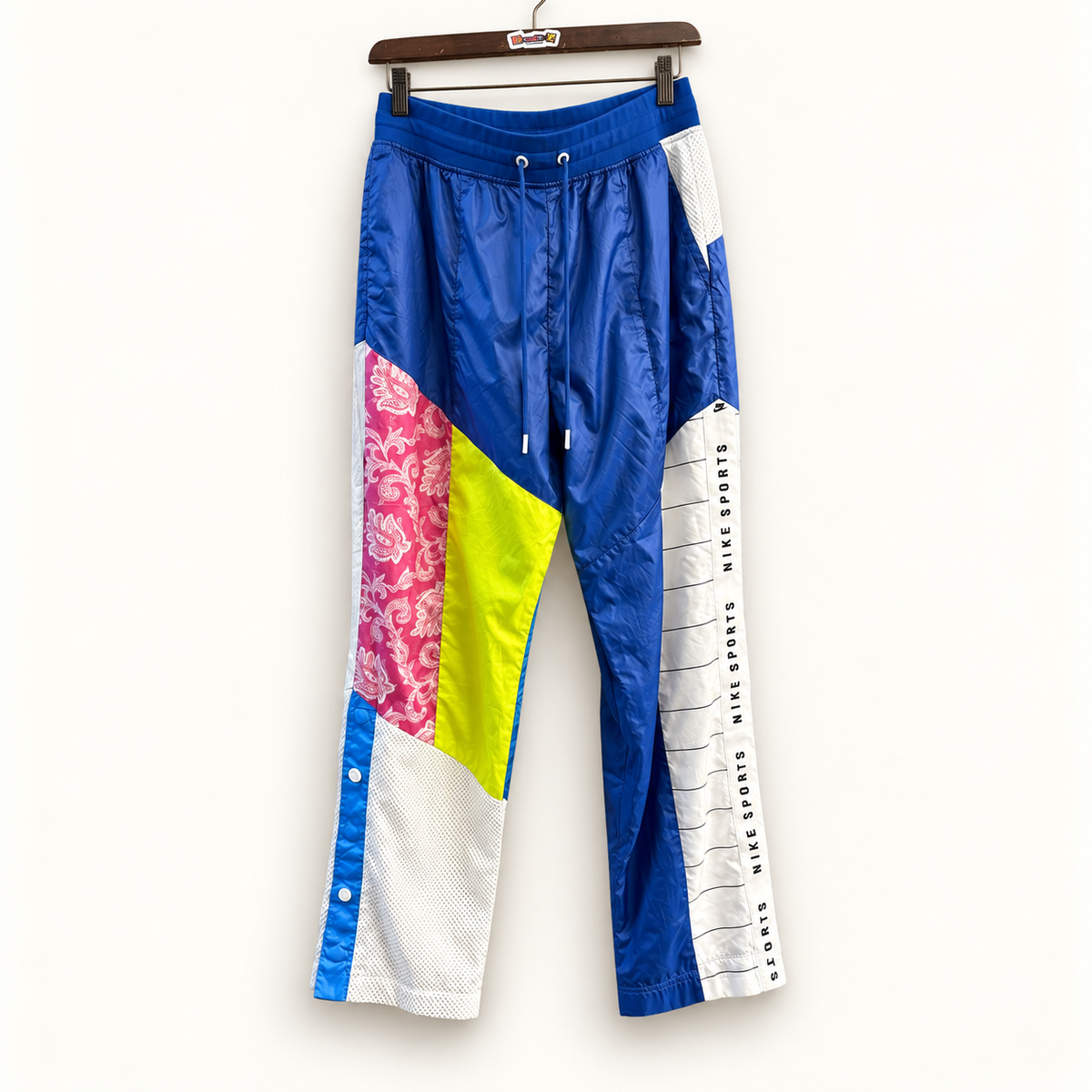 Nike blue multicolor color block windbreaker pants on warm off white editorial background