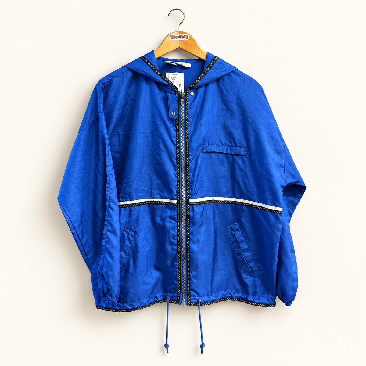 Tail vintage blue windbreaker jacket on warm off white editorial background