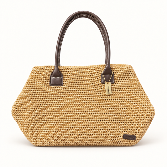 The Sak woven tan tote with brown handles on off white background